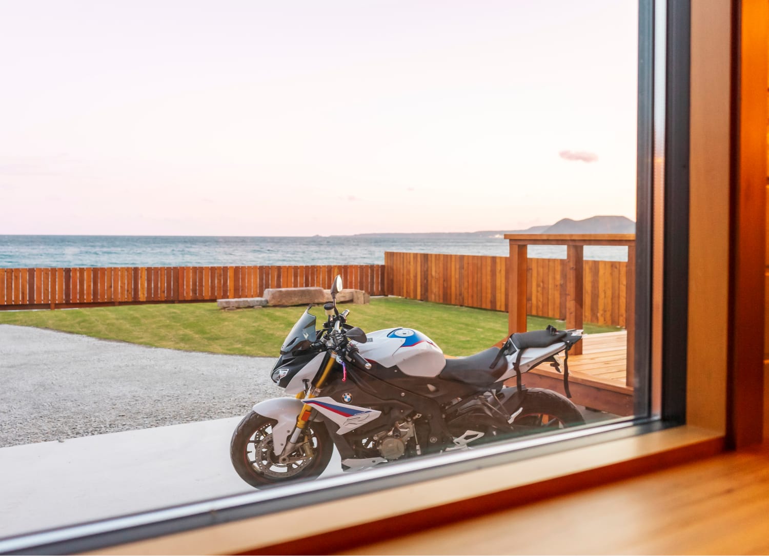 部屋の窓からバイクと海が見える景色